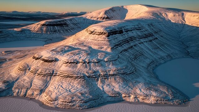 Aerial view of snow covered mountain peaks and frozen lakes at sunset