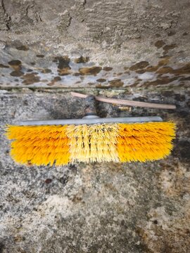 Yellow cleaning brush head lying on a textured concrete ground
