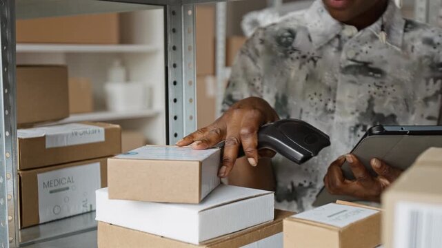 African American young adult woman scanning medical boxes with barcode reader and holding tablet in warehouse. Clip is perfect for logistics and healthcare supply chain presentations