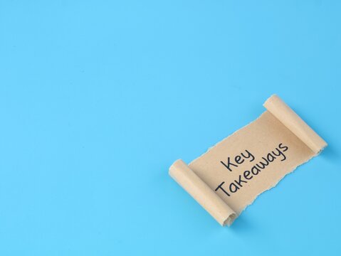 Key takeaways text handwritten on a brown paper scroll over bright blue background. Perfect concept for main points, business summaries, learning conclusions, and key points overview