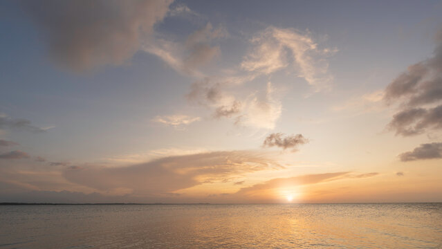 Sunset sky clouds over sea water background in evening with orange, blue sun light, Horizon sea ocean sunrise sky landscape nature backgrounds and gold sun down in golden hour summer season, Dusk sky