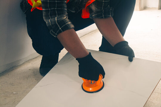 The craftsman uses a suction cup to lift the tile for work.