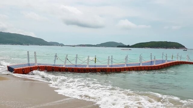 long plastic pontoon swaying on strong sea waves near shore. floating pontoon with railings bending under wave pressure at beach. concept of pontoon instability and sea power in resort bay