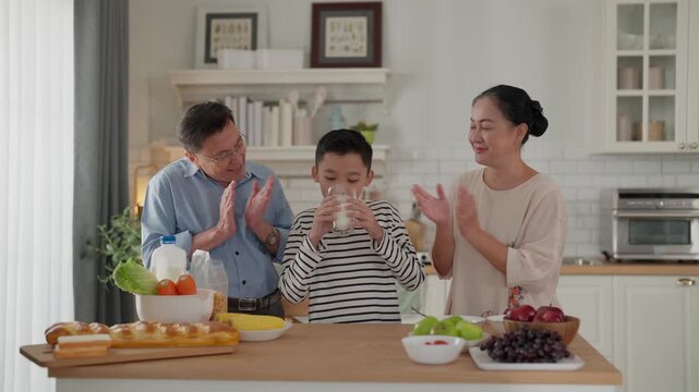 Happy asian family in kitchen sharing breakfast across table, smiling with father, milk, fruit, and bread in bright home interior morning meal