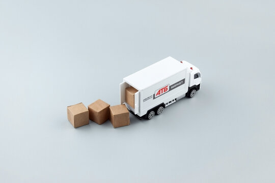 White toy truck with ATB emblem with boxes on light background, space for text.