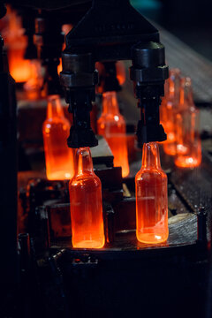 Industrial Robot Gripper Holding Hot Glowing Glass Bottles