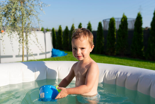 Toddler boy playing in inflatable pool during summer