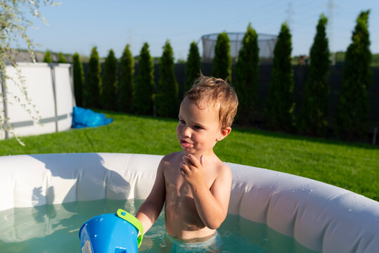 Toddler boy playing in backyard inflatable pool