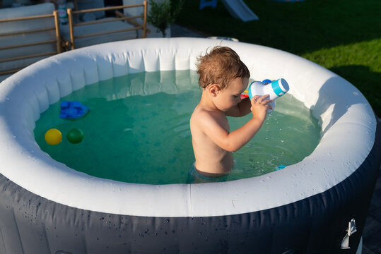 Toddler boy playing with water in inflatable pool