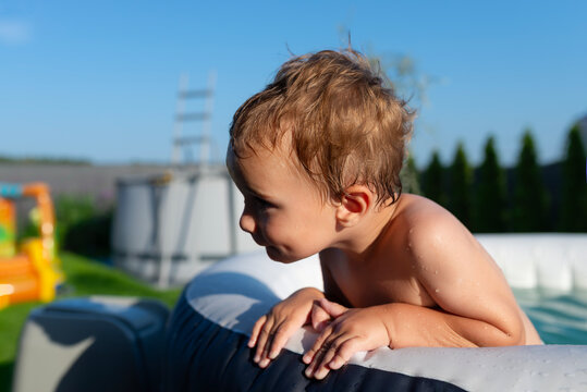 Toddler boy enjoying water play in inflatable pool