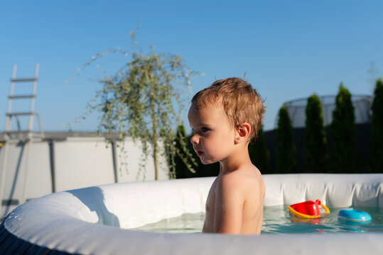 Toddler boy playing in inflatable backyard pool