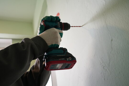 Low angle of hands using brushless cordless drill on wall