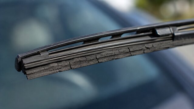 Macro close-up of aging windshield wiper blade showing cracked and deteriorated rubber edge