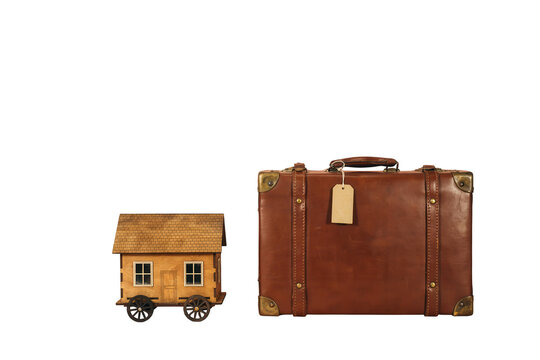 Portable Life on the Go A Charming Tiny House with Wheels Juxtaposed Beside a Robust, Classic Leather Suitcase, Evoking Ideas of Travel, Home, and Personal Mobility