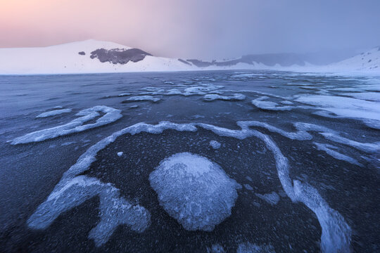 View of the frozen, snow-covered landscape with intricate ice patterns on the surface of the Piano Grande near Castelluccio, Umbria, Italy.