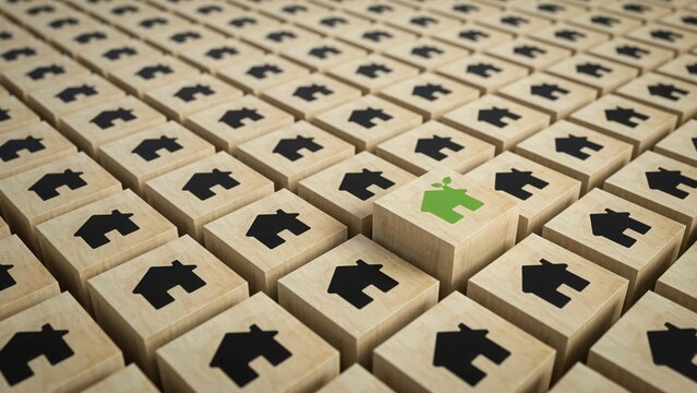 Green wooden block with house symbol among many wooden blocks with black house icons property investment
