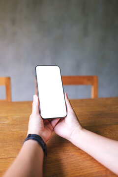 Vertical mockup image of a woman holding mobile phone with blank desktop screen