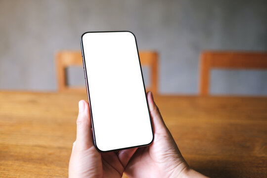 Mockup image of a woman holding mobile phone with blank desktop screen