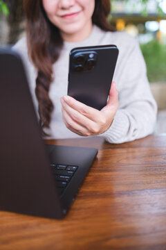 Vertical closeup image of a businesswoman using smart phone and laptop computer