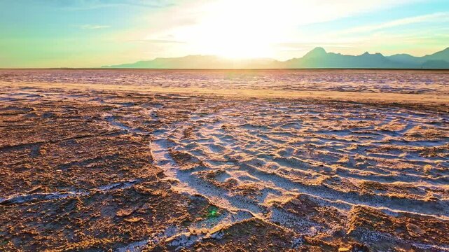 Tire tracks forming circular patterns on white salt crust beneath glowing golden sunset skies in Utah