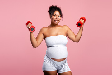 Fototapeta premium Pregnant woman exercising with dumbbells for fitness and health