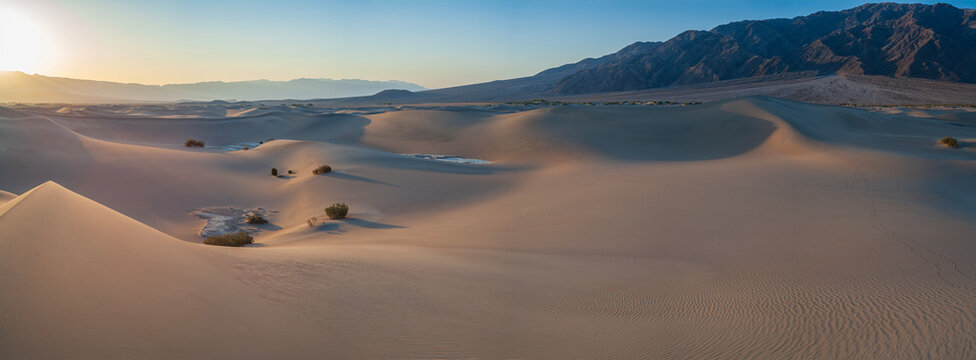 Beautiful wide panorama of sand dunes with sharp shadows and desert mountains