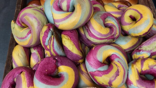 Rainbow and sesame bagels filling a bakery display