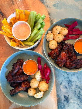 Top view of delicious crispy chicken wings served with dipping sauces and fresh crunchy vegetables, perfect for a casual meal, appetizer, party snack, or comfort food concept.