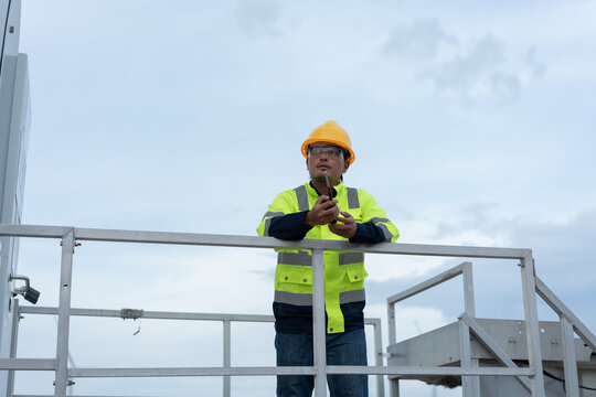 Wind turbine technician using a two way radio on an elevated maintenance platform, representing field communication, industrial safety, technical coordination and renewable energy operations.