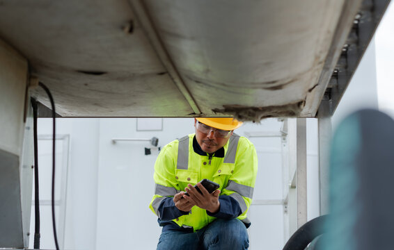 Industrial technician checking a smartphone during wind turbine equipment inspection, representing digital maintenance, condition monitoring, field diagnostics and renewable energy service.