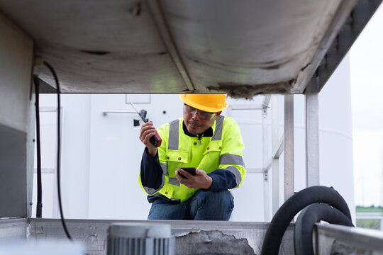 Maintenance technician using a radio and smartphone while inspecting wind turbine equipment, representing field coordination, remote support, troubleshooting and renewable energy service.