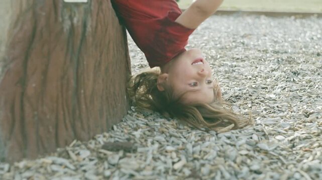 Boy hanging upside down from a playground structure and laughing