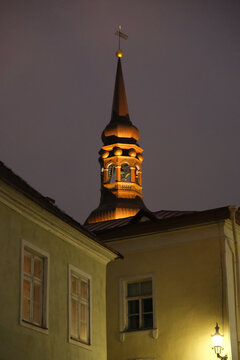 Low angle view of illuminated St. Nicholas Church spire in Tallinn Old Town at night.