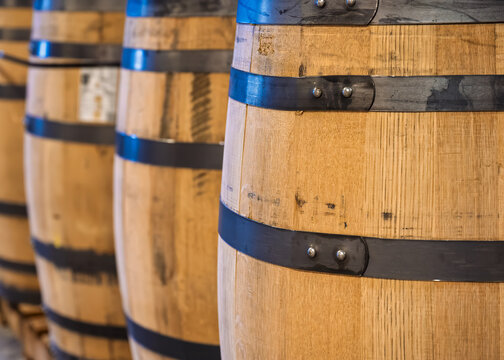 A ROW OF BURBON BARRELS LINED UP WITH SELECTIVE FOCUS ON HT EFRONT BARREL AT THE JEPTHA CREED DISTILLERY LOUISVILLE KENTUCKY