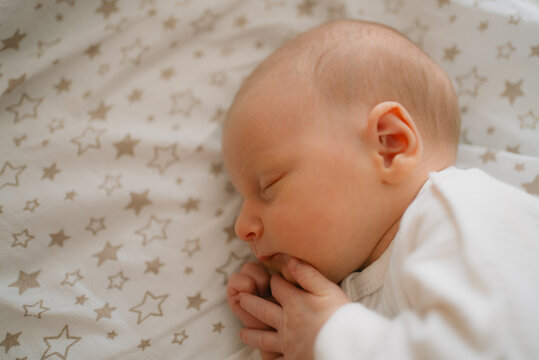 Newborn baby deep in slumber on a cozy mattress with a subtle star pattern, embodying the innocence and early developmental stages of childhood