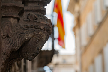 Detailed Stone Carved Face Sculpture with Blurred Catalan Flag © Roberto