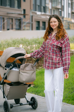Woman walking a stroller outdoors, portraying motherhood, childcare, and lifestyle in a modern urban setting, capturing the experience of a new generation parent navigating city life with a baby