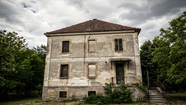 Old abandoned stone house in a rural setting under cloudy sky