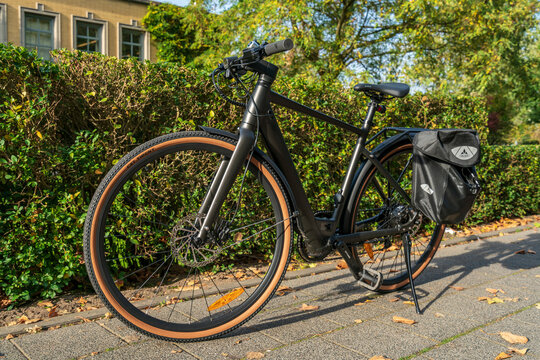 Dordrecht, Netherlands, October 19, 2025: Fiido C21 electric gravel bicycle with Vaude rear travel bag parked outside Villa Agustus, illustrating sustainable urban travel and cycling lifestyle.