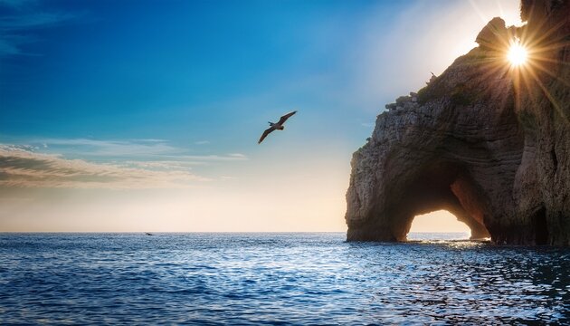 dramatic natural cave formation illuminated by sunbeams on a calm blue sea with a bird flying