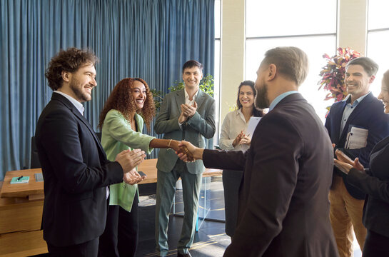 Business colleagues team witness handshake meeting partnership success. Executives and staff clap to welcome a partner, marking a closed agreement in office. Team trust wins key goals.