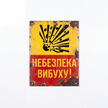 Close-up of a weathered, rusty metal warning sign featuring an explosion symbol and Ukrainian text "&ETH;&ETH;&bull;&ETH;&lsquo;&ETH;&bull;&ETH;&mdash;&ETH;&Yuml;&ETH;&bull;&ETH;&scaron;&ETH; &ETH;&rsquo;&ETH;&tilde;&ETH;&lsquo;&ETH;&pound;&ETH;&yen;&ETH;&pound;!" (DANGER EXPLOSION!) isolated on a white background.