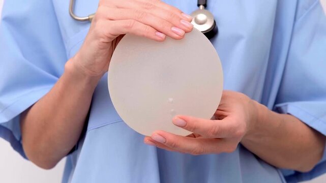 A surgeon presenting silicone breast implants in a medical office, healthcare consultation, plastic surgery, aesthetic medicine.