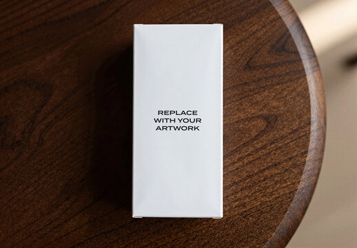 Vertical product packaging mockup on a dark wooden table surface, rectangular box for branding and graphic design display with placeholder text, realistic presentation in an interior setting