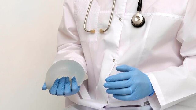 Surgeon demonstrating breast implant profiles and textures during a medical consultation, plastic surgery and aesthetic medicine clinic, augmentation mammoplasty patient choice.