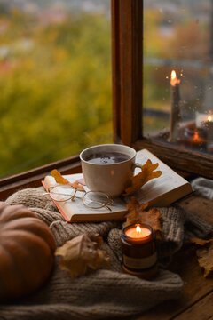 Cozy Fall Scene with Steaming Mug, Open Book, Pumpkin, and Burning Candle