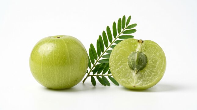 A whole green amla berry next to a half-sliced amla revealing the seed inside and a green leaf on white background.