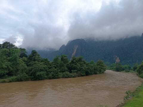 Scenic landscape of Nam Song River and limestone karst mountains with clouds in Vang Vieng, Laos.