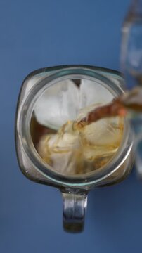 Iced Black Coffee Pouring Into a Cup Filled With Ice Cubes.
