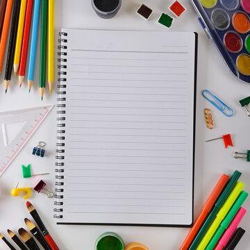 Top View of Open Spiral Notepad Mockup on White Table with Paints Brushes and Pencils
